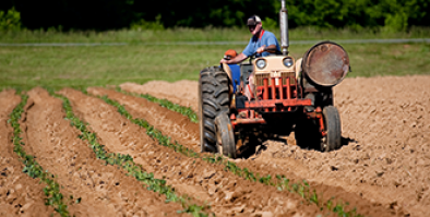 man riding on a tractor, plowing a field.