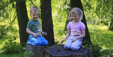 Two children sitting on stumps. 