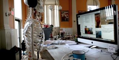 skeleton working at a desk and using a computer.