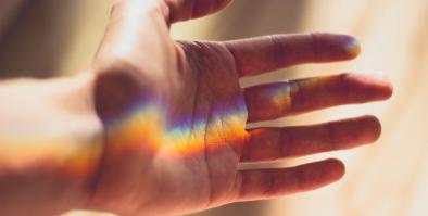 An open hand with a rainbow reflected on it