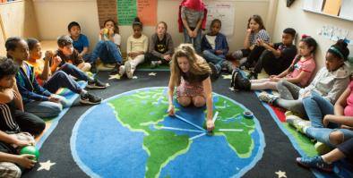 Students and teacher on globe rug