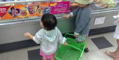 Two small children looking at refrigerated foods at a supermarket
