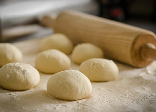 Balls of dough next to a wooden rolling pin