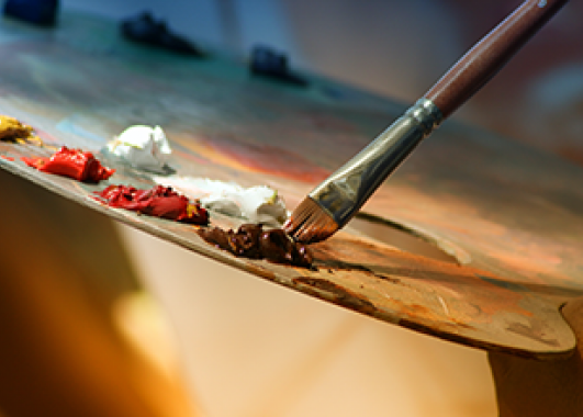 A paintbrush mixing paint on a paint pallet