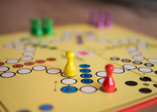 Board game with red, yellow, green and purple game pieces.
