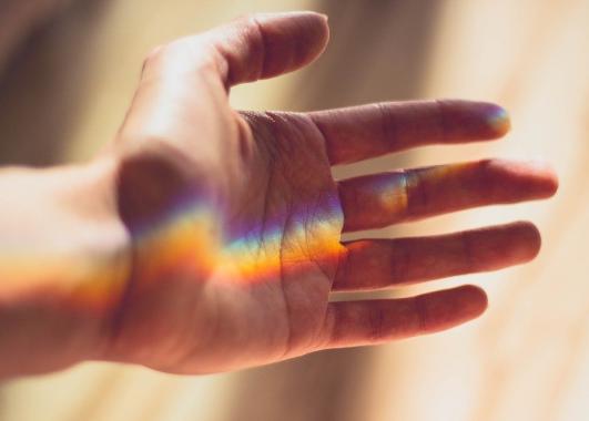 An open hand with a rainbow reflected on it