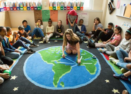 Students and teacher on globe rug