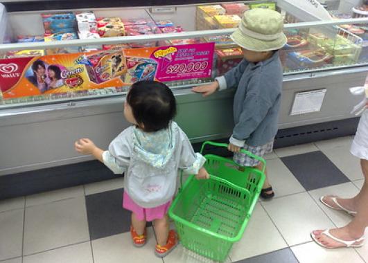 Two small children looking at refrigerated foods at a supermarket